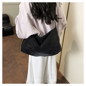 Dettaglio della borsa hobo in pelle opaca nera indossata a spalla, stile minimale