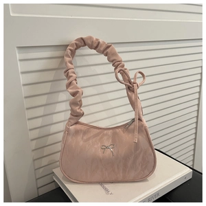 Detailed close-up of light pink handbag with silver butterfly charm and ruched handle