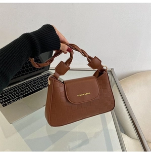Detail of dark brown baguette bag with checkered embossing and braided strap decoration