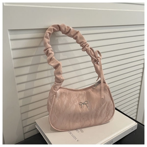 Macro shot of silver butterfly buckle on soft pink pleated cloud fabric handbag
