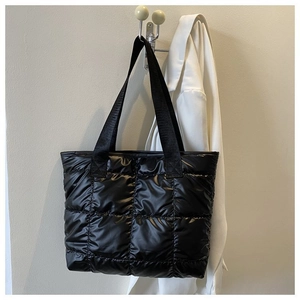 Macro detail of black quilted puffer tote bag fabric with plush square stitching pattern