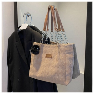 Dettaglio della borsa tote in pelle scamosciata kaki con texture trapuntata e ciondolo