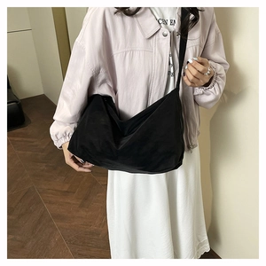 Dettaglio di una borsa tote nera in nylon a mezzaluna indossata da una modella in interni