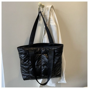 Detail of black quilted puffer tote bag with spacious design and dual strap handles