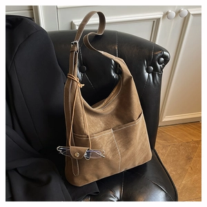 Detail of a brown suede tote bag featuring white contrast stitching and a side glasses pouch
