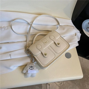Chic beige retro crossbody bag with cute bear embroidery and plush charm on the table
