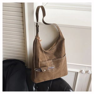 Detail of dark brown suede tote bag with white contrast stitching and decorative glasses