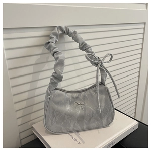 Detail of silver pleated handbag with metallic bow buckle and ruched handle design