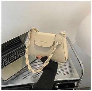 Close-up of cream shoulder bag with checkerboard embossing and braided handle strap