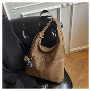 Close-up of matte tan tote bag showing contrast white stitching and premium texture