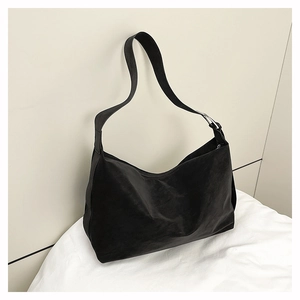 Detail of black matte hobo bag with silver metal buckle on a white cloth surface