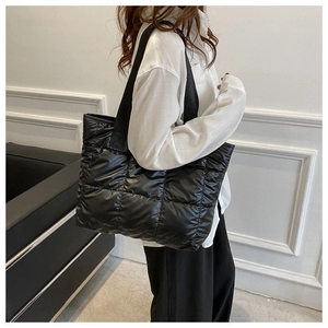 Quilted black down tote bag with a diamond stitch pattern worn by a model on shoulder