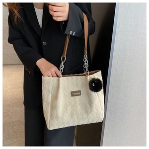 Dettaglio della borsa tote beige trapuntata con tracolla in pelle e pompon nero