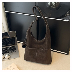 Detail of dark brown matte hobo bag with contrast stitching and mini charm pendant