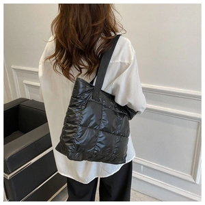 Detailed back view of a black quilted puffer tote bag on model for casual styling