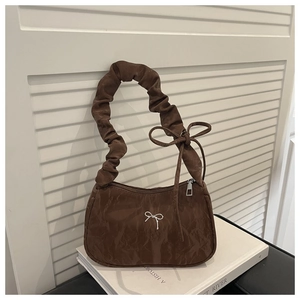 Detail of coffee brown ruched underarm bag featuring a silver butterfly charm and textured nylon