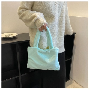 Detail shot of the plush mint green handbag's soft faux fur texture and wide handles
