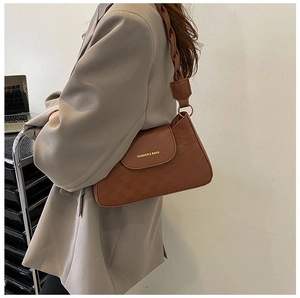 Detail of a brown shoulder bag with woven strap and gold Fashion & Bags lettering