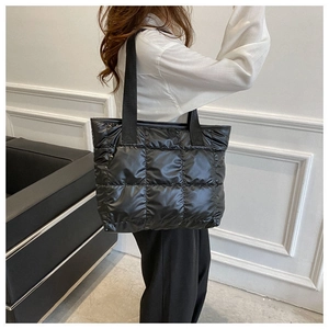 Quilted black puffer tote bag shown on a model with minimalist interior background