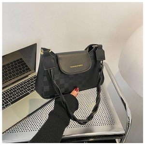Detail of black checkered embossed leather bag with woven handle and gold magnetic closure