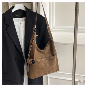 Detail of retro matte brown hobo tote with white stitching and mini charm on strap