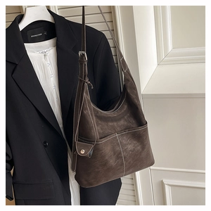 Close-up of deep brown suede tote with white contrast stitching and mini pouch accessory