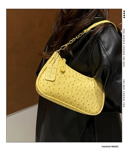 Detail of yellow ostrich texture underarm bag with gold chain and leather strap