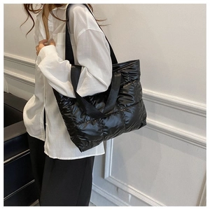 Close-up of black quilted puffer tote bag with wide straps and puffy padded texture