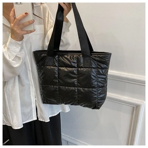 Detail of black quilted puffer tote bag in shiny nylon with soft padded texture