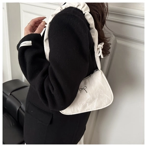 Detail of white butterfly underarm bag with pleated texture on black jacket shoulder
