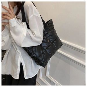 Detail of black quilted puffer tote bag with wide strap handles for daily use