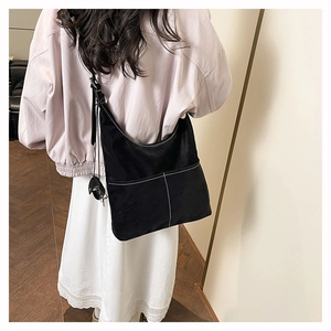 Detail of black hobo bag with contrast white stitching and adjustable shoulder strap