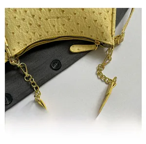 Detail of yellow ostrich texture faux leather bag with gold chain strap and zipper