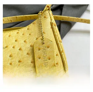 Detailed macro view of yellow ostrich texture leather handbag with gold metal tag accessory