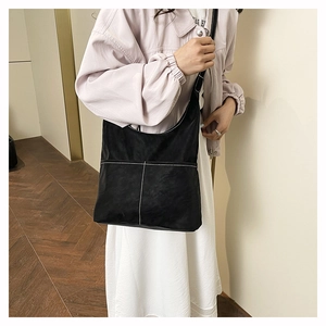 Detail of black leather tote bag with white contrast stitching and adjustable strap