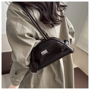 Detail of dark brown glossy underarm bag with silver plaque and polished leather texture