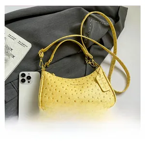 Top view of yellow ostrich pattern hobo bag with gold hardware on grey suit