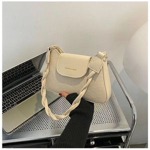 Detail of beige shoulder bag with checkered texture and braided handle design