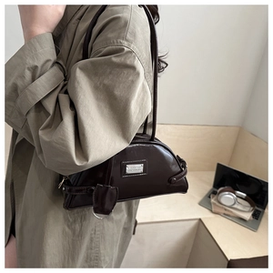 Close-up of a dark brown glossy leather underarm bag featuring fine stitching details