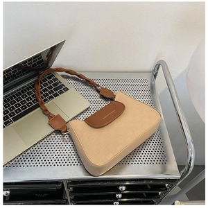 Detail of cream faux leather crossbody bag featuring textured grid and woven strap