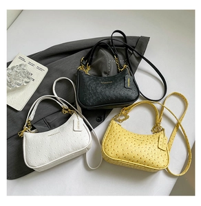 Detailed trio of ostrich pattern underarm bags in black, white, and yellow with gold chains