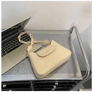 Detail of a beige textured shoulder bag with a woven strap on an office desk