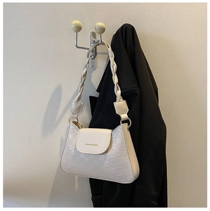 Detail of cream white faux leather bag with lattice texture and braided strap