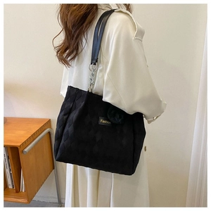 Dettaglio della borsa tote nera trapuntata con catene argentate e logo Fashion sul lato