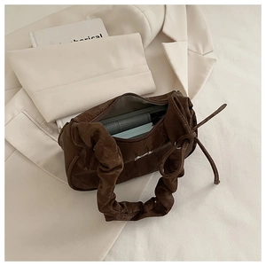Detailed interior of brown pleated handbag showing spacious compartment and zip closure