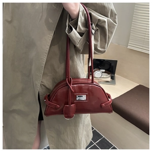 Detail of red patent leather half-moon shoulder bag with silver logo and slender straps