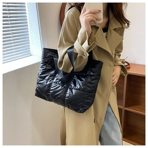 Detail of black quilted puffer tote bag with glossy finish on a stylish model