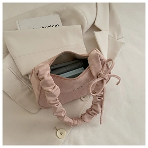 Pink pleated handbag with bow detail showing spacious interior for phone and wallet
