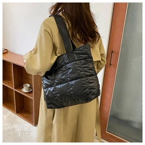 Quilted black puffer tote bag shown on shoulder in a retro indoor lifestyle setting