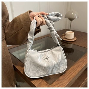 Detail of silver pleated crescent bag with metallic bow and ruffled handle decoration